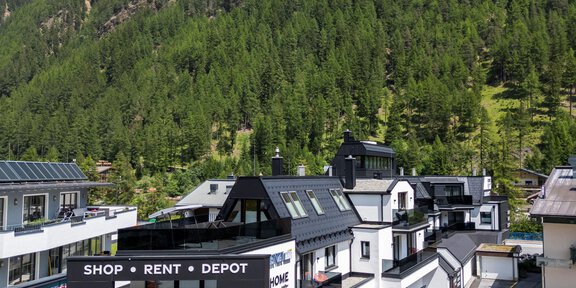 Ein modernes Sportgeschäft in einem Bergdorf, umgeben von grünen Bergen. Der Himmel ist klar und es gibt viel Tageslicht. - Sport4You Filiale Giggijoch - Sölden