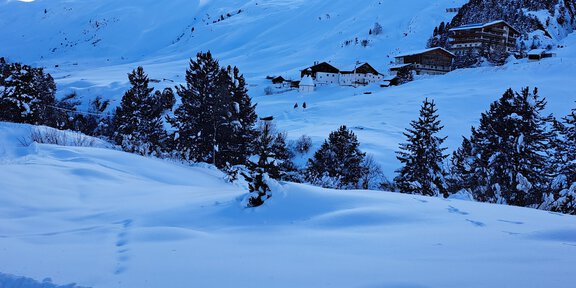 A snowy landscape with high mountains in the background. In the foreground are trees and huts covered in snow during winter. - Hängebrücke in Rofen - Vent
