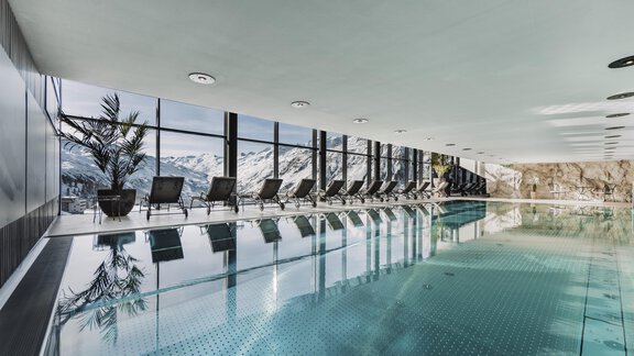 Ein eleganter Innenpool mit Blick auf die Berge. Die große Glasfront lässt viel Licht herein und schafft eine entspannende Atmosphäre. - SKI | GOLF | WELLNESS Hotel Riml - Hochgurgl