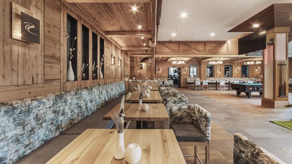 Ein eleganter Innenraum mit Holzverkleidungen und gemütlichen Sitzbereichen. Die Tische sind ordentlich gedeckt und es gibt eine entspannte Atmosphäre. - SKI | GOLF | WELLNESS Hotel Riml - Hochgurgl