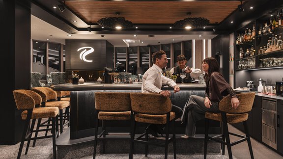 Eine elegante Bar mit modernen Möbeln und stilvollem Ambiente. Zwei Personen sitzen am Bartresen und genießen ihre Zeit. - SKI | GOLF | WELLNESS Hotel Riml - Hochgurgl