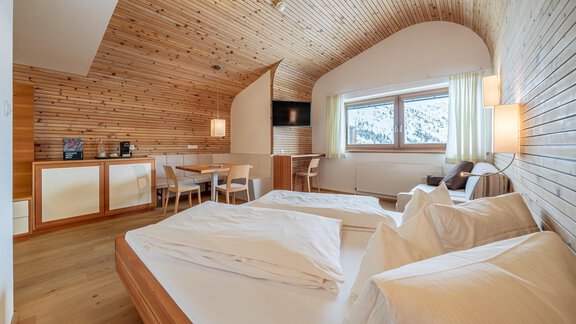 Ein modernes Schlafzimmer mit Holzverkleidung und großen Fenstern. Zwei Einzelbetten und ein kleiner Tisch mit Stühlen sind ebenfalls sichtbar. - Hotel Hochsölden - Hochsölden