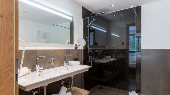 Ein modernes Badezimmer mit zwei Waschbecken und einer großen Glasdusche. Die Wände sind elegant in dunklen Farbtönen gehalten. - Alpenappartement Central Valley Penthouse - Längenfeld