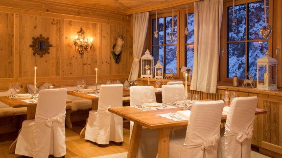 A cozy restaurant with wooden paneling and elegant tables. The rooms are atmospherically decorated with candles and curtains. - Art & Relax Hotel Bergwelt - Obergurgl 