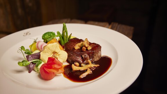 An artfully arranged plate with a juicy piece of meat, surrounded by colorful vegetables and a rich sauce. The dish presents itself appetizingly and appealingly. - Art & Relax Hotel Bergwelt - Obergurgl 