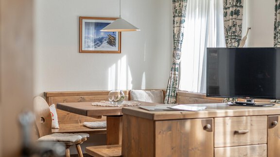 Ein gemütlicher Wohnraum mit Holzmöbeln und einem Fernseher. Ein Tisch mit Stühlen lädt zum Entspannen ein. - Ferienwohnung Alt Poschach - Obergurgl 