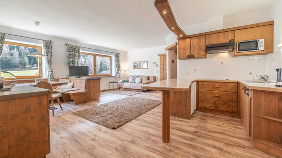 Eine moderne Küche mit Holzdetails und einem offenen Wohnbereich. Große Fenster bieten einen Blick auf die grüne Landschaft. - Ferienwohnung Alt Poschach - Obergurgl 