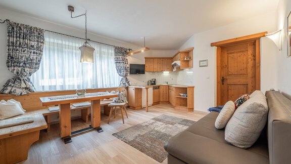 Ein helles und gemütliches Wohnzimmer mit einer modernen Küchenzeile. Es gibt einen Essbereich mit Holzbank und einen bequemen Sofa. - Ferienwohnung Alt Poschach - Obergurgl 