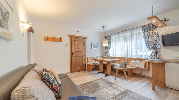 Ein gemütliches Wohn-Esszimmer mit einem Sofa und einem Holztisch. Der Raum hat große Fenster, die für viel natürliches Licht sorgen. - Ferienwohnung Alt Poschach - Obergurgl 