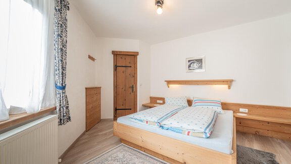 Ein gemütliches Schlafzimmer mit einem großen Bett und holzernen Möbeln. Helle Fenster sorgen für ein freundliches Ambiente. - Ferienwohnung Alt Poschach - Obergurgl 