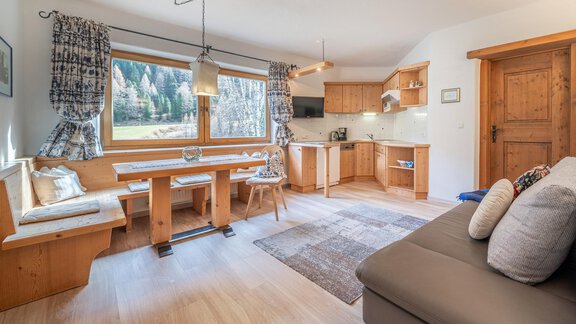 Eine helle und einladende Küche mit Holzvertäfelungen und einem großen Fenster. Der Essbereich bietet Platz für mehrere Personen und ist gemütlich eingerichtet. - Ferienwohnung Alt Poschach - Obergurgl 