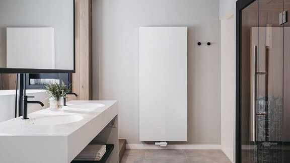 A modern bathroom with an elegant vanity unit and a large mirror. The walls are bright, and a glass shower is located in the corner. - The Crystal VAYA Unique - Obergurgl 