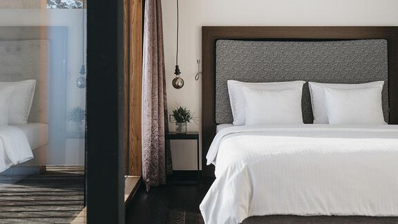 A modern bedroom with a large bed and white pillows. The room design is bright and inviting, with a large window that lets in daylight. - The Crystal VAYA Unique - Obergurgl 