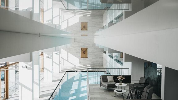 A modern interior with a swimming pool and stylish furniture. Bright walls and large windows create a pleasant atmosphere. - The Crystal VAYA Unique - Obergurgl 