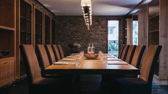 A stylish conference room with a long wooden table and comfortable chairs. The walls are clad in natural stone, and there is plenty of natural light. - The Crystal VAYA Unique - Obergurgl 