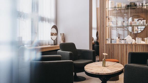 A modern and elegant interior with cozy armchairs and a round wooden table. In the background, there is a display cabinet with decorative objects. - The Crystal VAYA Unique - Obergurgl 