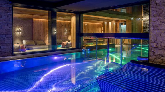 An elegant interior with a pool and gently shimmering water. The atmosphere is relaxing and modern, with stylish lighting. - Alpengasthof Grüner - Sölden