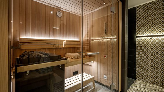 A modern sauna with wood paneling and glass walls. The room provides a relaxing atmosphere with soft lighting. - Alpengasthof Grüner - Sölden