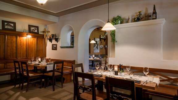 A cozy restaurant with wooden furniture and elegantly laid tables. The warm colors and stylish lighting create an inviting atmosphere. - Alpengasthof Grüner - Sölden