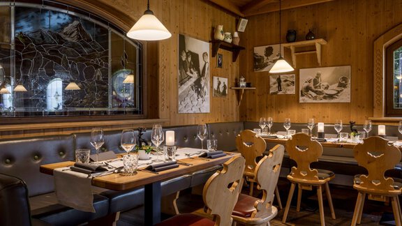 A cozy restaurant with wooden-paneled walls and an inviting atmosphere. The tables are elegantly set and decorated. - Alpengasthof Grüner - Sölden