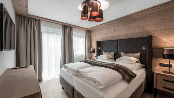 Ein modernes Schlafzimmer mit einem großen Bett und stilvollen Möbeln. Große Fenster lassen viel Licht herein und schaffen eine gemütliche Atmosphäre. - AlpenParks The Secret Sölden - Sölden