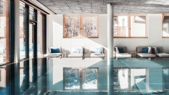 Ein moderner Innenpool mit klaren Linien und einladenden Liegen. Große Fenster lassen viel Licht herein und bieten einen schönen Ausblick. - AlpenParks The Secret Sölden - Sölden