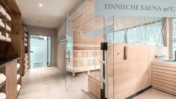 Ein heller und moderner Wellnessbereich mit einer finnischen Sauna bei 90°C. Große Fenster lassen viel Tageslicht herein und die Wände sind aus hellem Holz. - AlpenParks The Secret Sölden - Sölden
