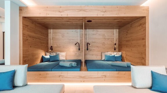 Ein modernes Schlafzimmer mit zukunftsweisendem Design. Es enthält zwei gemütliche Betten in einem Holzrahmen und blaue Kissen. - AlpenParks The Secret Sölden - Sölden