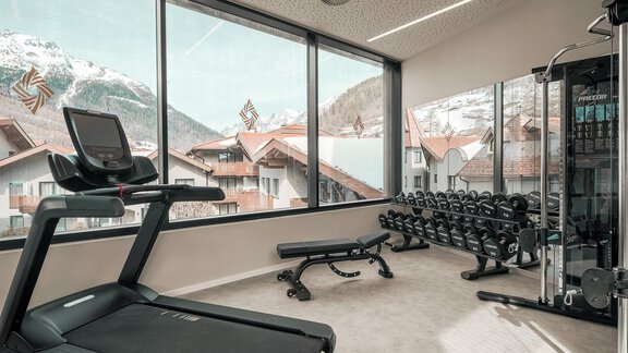 Ein modernes Fitnessstudio mit Blick auf schneebedeckte Berge. Es gibt ein Laufband und eine Hantelbank mit verschiedenen Gewichten. - AlpenParks The Secret Sölden - Sölden