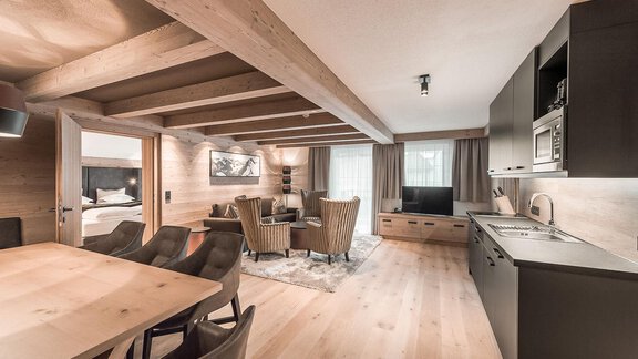 Ein modernes Wohn- und Esszimmer mit Holzbalken und eleganter Einrichtung. Die offene Küche fügt sich harmonisch in den Raum ein und sorgt für eine gemütliche Atmosphäre. - AlpenParks The Secret Sölden - Sölden
