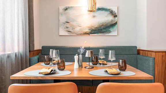Ein modernes Esszimmer mit einem Holztafel und eleganten Stühlen. Die Tischdeko umfasst Gläser, Servietten und einen stilvollen Wandkunstwerk. - AlpenParks The Secret Sölden - Sölden