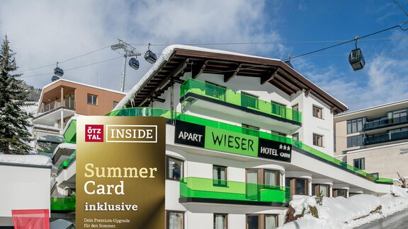 A modern building named "Apart Wieser" in a snow-covered landscape. In the foreground, there is a sign for the inclusive summer card. - Apart Hotel Garni Wieser - Sölden