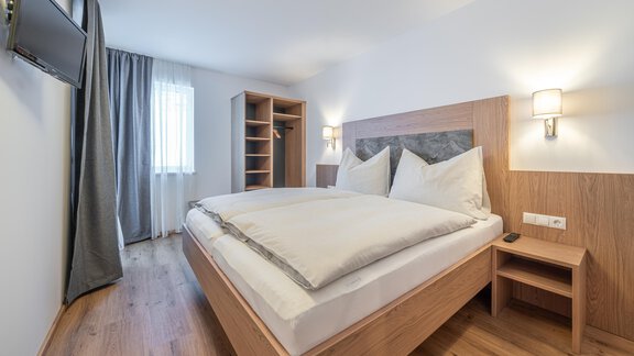 Ein modernes Schlafzimmer mit einem großen Bett und Holzmöbeln. Der Raum ist hell und lädt zum Entspannen ein. - Apart Sonnenbichl - Sölden