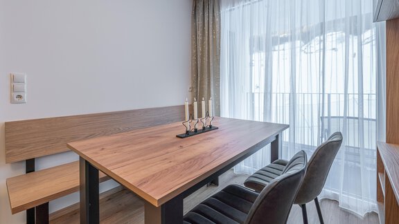Ein eleganter Essbereich mit einem Holztisch und einer Bank. Vorhänge lassen sanftes Licht herein und schaffen eine gemütliche Atmosphäre. - Apart Sonnenbichl - Sölden