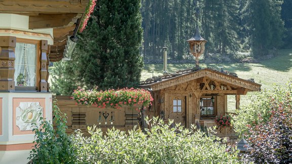 Ein malerisches Holzhaus umgeben von grünen Bäumen und bunten Blumen. Die idyllische Umgebung vermittelt ein Gefühl von Ruhe und Naturverbundenheit. - Apart Wiesengrund - Sölden