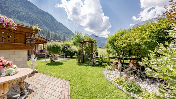 Ein schöner Garten mit grünem Gras und bunten Blumen. Im Hintergrund sieht man Berge unter einem blauen Himmel mit einigen Wolken. - Apart Wiesengrund - Sölden