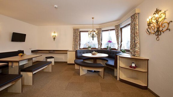 Ein gemütlicher Raum mit Sitzgelegenheiten und großen Fenstern. Ein runder Tisch in der Mitte lädt zum Verweilen ein. - Appartement Alpin - Sölden