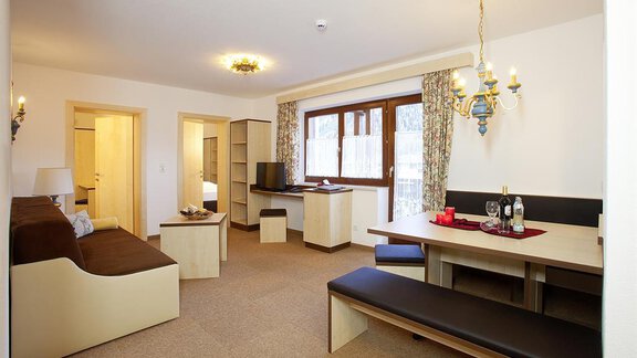Ein gemütlicher Wohnraum mit einem Sofa, einem Essbereich und einem großen Fenster. Die Einrichtung ist modern und hell gestaltet. - Appartement Alpin - Sölden