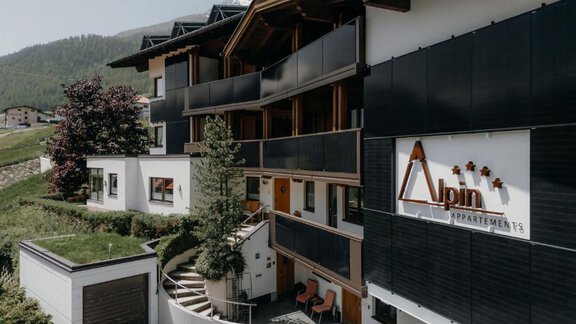 Ein modernes Gebäude mit dem Namen "Alpin Appartements" in einer bergigen Umgebung. Die Architektur ist stilvoll und es gibt einen schön gestalteten Außenbereich. - Appartement Alpin - Sölden