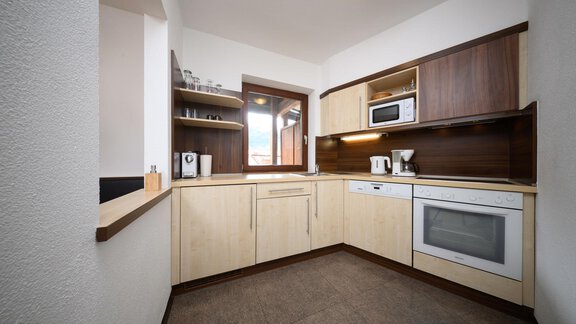 Eine moderne Küche mit Holzregalen und einer großen Fensterscheibe. Sie ist gut ausgestattet mit Geräten wie einem Kühlschrank und einer Mikrowelle. - Appartement Alpin - Sölden