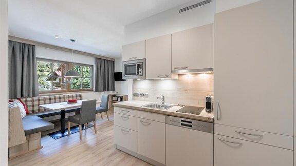 Eine moderne Küche mit hellen Schränken und einem Essbereich. Das Zimmer ist freundlich und gut beleuchtet, mit Blick auf einen schönen Außenbereich. - Appartement Cristallo - Sölden