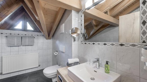 Ein modernes Badezimmer mit Holzdecke und weißen Fliesen. Der Waschbereich ist mit einem eleganten Waschbecken und einem großen Spiegel ausgestattet. - Appartement Cristallo - Sölden