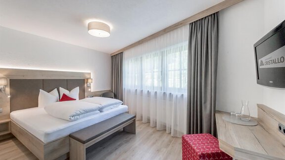 Ein modernes Schlafzimmer mit einem großen Bett und frischen weißen Bettdecken. Der Raum hat helle Wände und einen großen Fenster mit Vorhängen. - Appartement Cristallo - Sölden