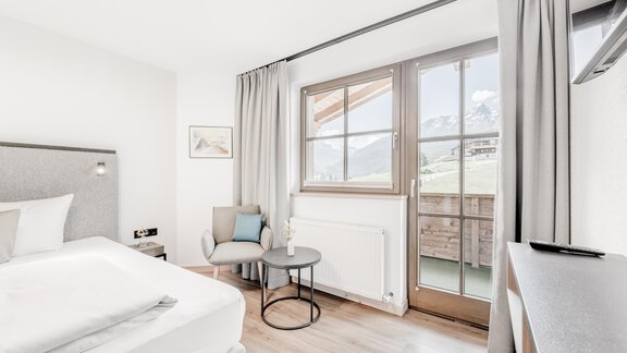 Ein modernes Schlafzimmer mit einem großen Fenster und einem gemütlichen Sessel. Die helle Einrichtung schafft eine einladende Atmosphäre. - Appartement Montanara - Sölden
