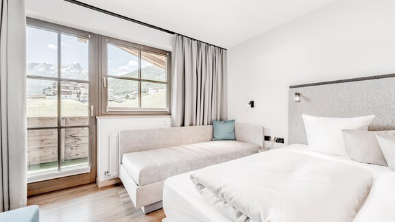 Ein modernes Schlafzimmer mit einem großen Fenster und einem bequemen Bett. Die Einrichtung ist hell und freundlich, mit einem gemütlichen Sitzbereich. - Appartement Montanara - Sölden