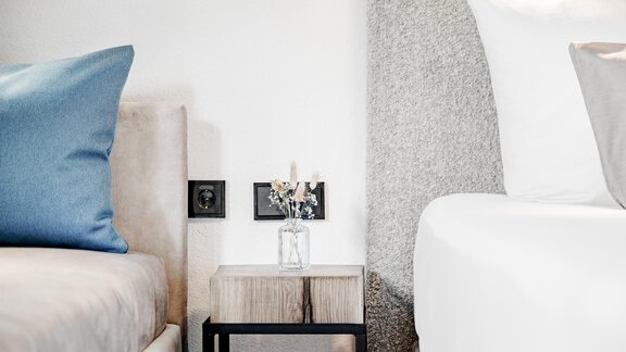 Ein modernes Schlafzimmer mit zwei Betten. Auf dem Nachttisch steht eine kleine Vase mit Trockenblumen. - Appartement Montanara - Sölden