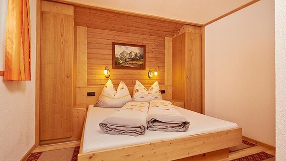 Ein gemütliches Schlafzimmer mit Holzinterieur. Das Bett ist mit weichen Kissen dekoriert und es gibt ein schönes Gemälde an der Wand. - Appartement Schwalbennest - Sölden