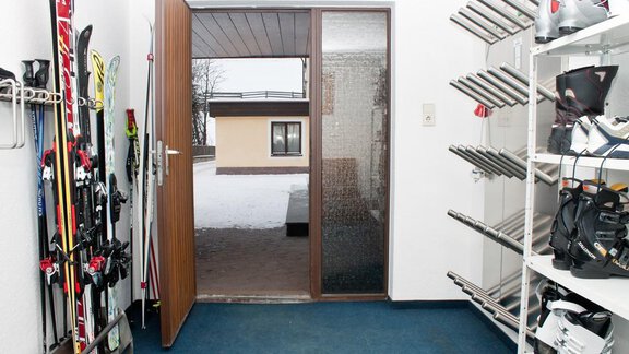 Ein Eingangsbereich mit Skiern und Skischuhen an der Wand. Durch die Glas-Tür sieht man den schneebedeckten Außenbereich. - Appartement Viertler - Sölden