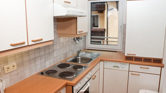 Eine moderne Küche mit Holzoberflächen und einem Fenster. Die Ausstattung umfasst einen Herd, eine Spüle und ausreichend Stauraum. - Appartement Viertler - Sölden