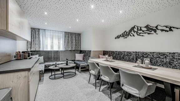 A modern, stylish room with a cozy seating area and a spacious table. The wall decoration features a mountain motif and the lighting is pleasantly bright. - Appartementhaus Kathrin - Sölden